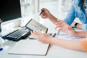 This is an image of 2 people who can't be seen holding an electrical tablet and a pen. They appear to be having a discussion about what is being displayed on the screen.
