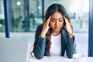 A person with their hands on their head with their face displaying stress